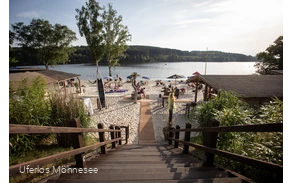 Holztreppe führt hinunter zu einem belebten Strand am Möhnesee.